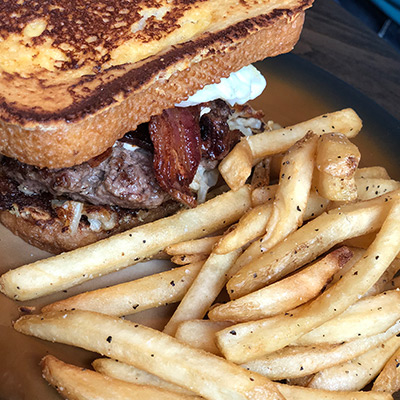 A grilled sandwich containing bacon accentuates a helping of French fries in Stillwater, MN.